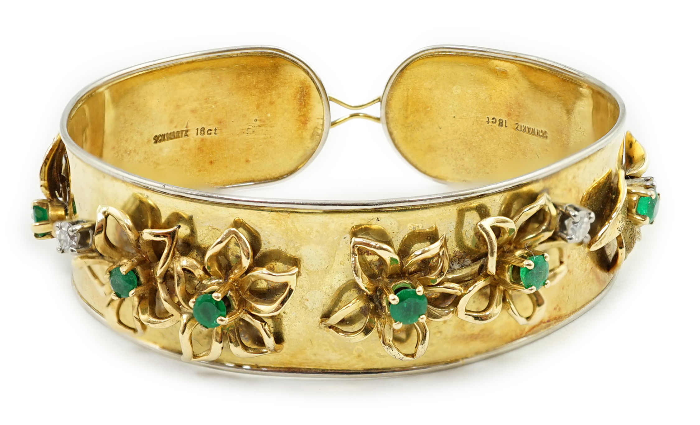 A recent Schwartz 18k gold, emerald and diamond cluster set open bangle with clasp